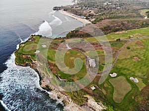 Aerial view of luxury golf course next the cliff, ocean and beach in Bali island, Indonesia.