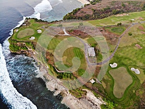 Aerial view of luxury golf course next the cliff, ocean and beach in Bali island, Indonesia.