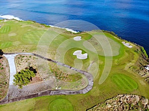 Aerial view of luxury golf course next the cliff, ocean and beach in Bali island, Indonesia.