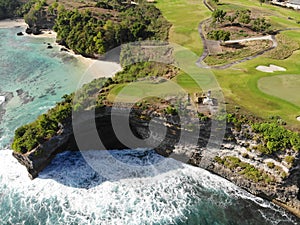 Aerial view of luxury golf course next the cliff, ocean and beach in Bali island, Indonesia.