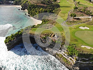 Aerial view of luxury golf course next the cliff, ocean and beach in Bali island, Indonesia.
