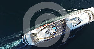 Aerial view of luxury medium cruise ship sailing from port on sunrise