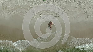 Aerial view of lying woman on the beach with her baby girl