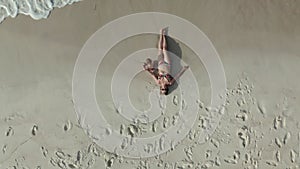 Aerial view of lying woman on the beach with her baby girl