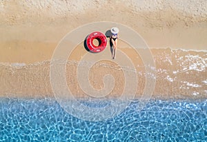 Aerial view of a lying woman in hat with red swim ring