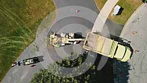 Aerial view of Maintenance worker loading cut tree branches into the wood chipper machine for shredding