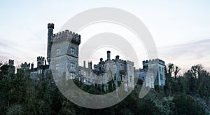 Aerial view of majestic Lismore Castle in County Waterford, Ireland, bathed in the golden glow of the setting sun