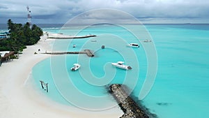 Aerial view of Maldives tropical island with pier and speed boats in blue ocean. Summer and travel vacation concept.