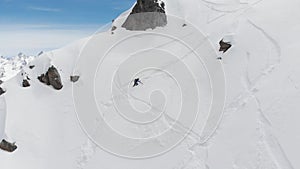 An aerial view of a male athlete athlete skier clambering up a steep slope up. Skitour freeride backcountry climbing