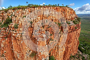 Aerial view of man holding Australian Flag on top of the iconic cliffs and high plateau of the Cockburn Range, El Questro Station