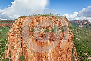 Aerial view of man holding Australian Flag on top of the iconic cliffs and high plateau of the Cockburn Range, El Questro Station