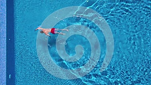 Aerial view of man in red shorts swims in the pool