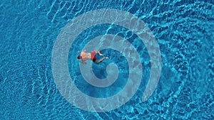 Aerial view of man in red shorts swims in the pool