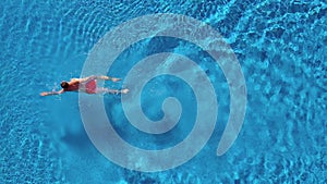 Aerial view of man in red shorts swims in the pool