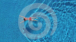 Aerial view of man in red shorts swims in the pool