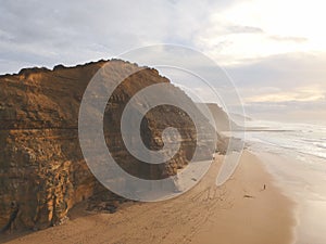 Aerial view from a man walking sandy beach at the sunset with an amazing cliff