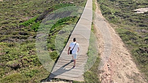 Aerial View Of A Man Walking To The Wooden Path On A Sunny Day