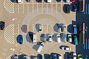 Aerial view of many colorful cars parked on parking lot with lines and markings for parking places and directions