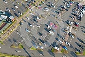 Aerial view of many colorful cars parked on parking lot with lines and markings for parking places and directions