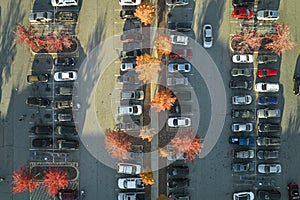 Aerial view of many colorful cars parked on parking lot with lines and markings for parking places and directions. Place