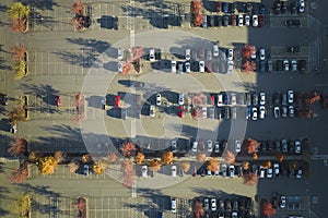 Aerial view of many colorful cars parked on parking lot with lines and markings for parking places and directions. Place