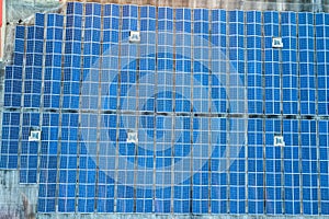 Aerial view of many photo voltaic solar panels mounted of industrial building roof