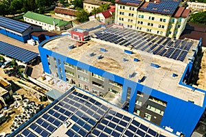 Aerial view of many photo voltaic solar panels mounted of industrial building roof