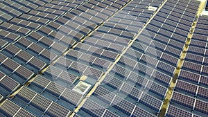 Aerial view of many photo voltaic solar panels mounted of industrial building roof.