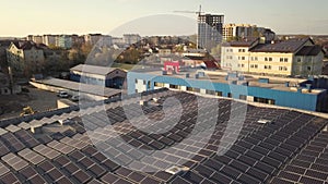 Aerial view of many photo voltaic solar panels mounted of industrial building roof.