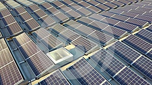 Aerial view of many photo voltaic solar panels mounted of industrial building roof.