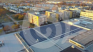 Aerial view of many photo voltaic solar panels mounted of industrial building roof.