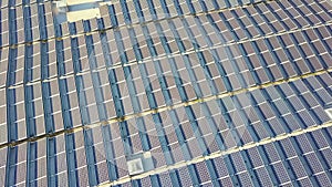 Aerial view of many photo voltaic solar panels mounted of industrial building roof.