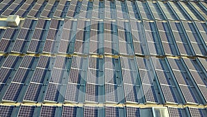 Aerial view of many photo voltaic solar panels mounted of industrial building roof.