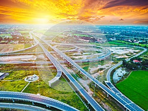 Aerial view of a massive highway intersection, Highway to city transport traffic road with vehicle movement at sunset.