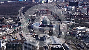 Aerial view of modern football stadium and busy multilane highway leading around. Large railroad yard in background