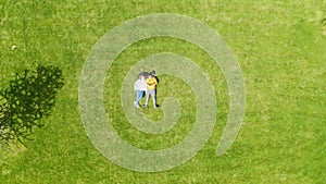 Aerial view of a modern recreation park. A couple in love lies on a green lawn among unique trees and plants. Galitsky