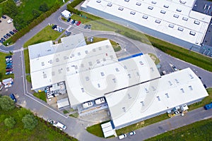 Aerial view of modern storage warehouse with solar panels on the roof. Logistics center in industrial city zone from drone view.