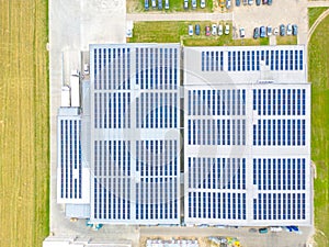 Aerial view of modern storage warehouse with solar panels on the roof. Logistics center in industrial city zone from drone view.