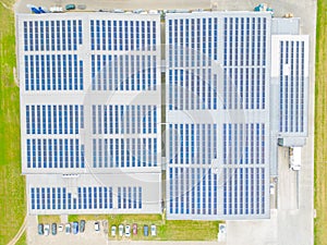 Aerial view of modern storage warehouse with solar panels on the roof. Logistics center in industrial city zone from drone view.