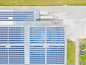 Aerial view of modern storage warehouse with solar panels on the roof. Logistics center in industrial city zone from drone view.