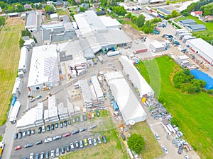 Aerial view of modern storage warehouse with solar panels on the roof. Logistics center in industrial city zone from drone view.