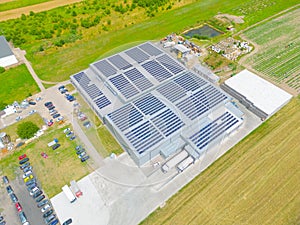 Aerial view of modern storage warehouse with solar panels on the roof. Logistics center in industrial city zone from drone view.