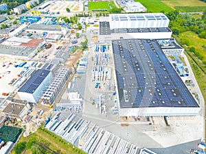 Aerial view of modern storage warehouse with solar panels on the roof. Logistics center in industrial city zone from drone view.