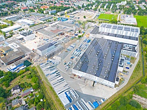 Aerial view of modern storage warehouse with solar panels on the roof. Logistics center in industrial city zone from drone view.