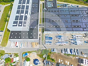 Aerial view of modern storage warehouse with solar panels on the roof. Logistics center in industrial city zone from drone view.