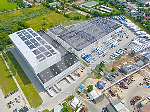 Aerial view of modern storage warehouse with solar panels on the roof. Logistics center in industrial city zone from drone view.