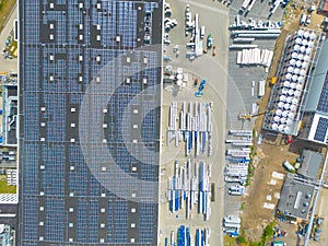 Aerial view of modern storage warehouse with solar panels on the roof. Logistics center in industrial city zone from drone view.