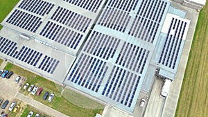 Aerial view of modern storage warehouse with solar panels on the roof. Logistics center in industrial city zone from drone view.