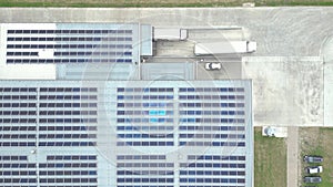 Aerial view of modern storage warehouse with solar panels on the roof. Logistics center in industrial city zone from drone view.