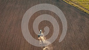 Aerial view modern tractor on the agricultural field on sunset time. Tractor plowing land and cultivating field.